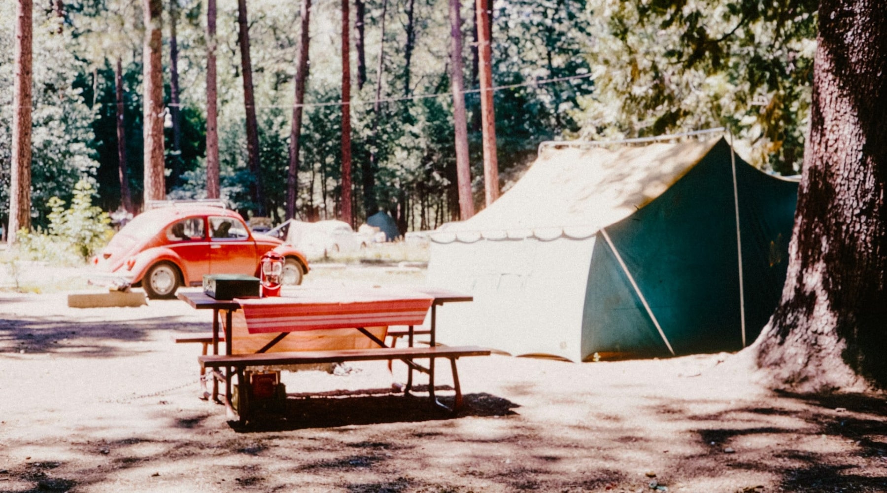 A photo of a camping site with a vintage car in the background.