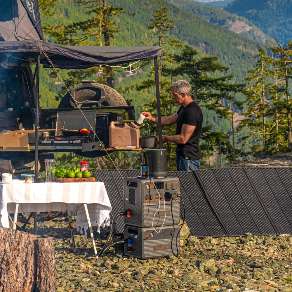 A photo of a man camping outdoors next to a bluetti ac240p portable power station.