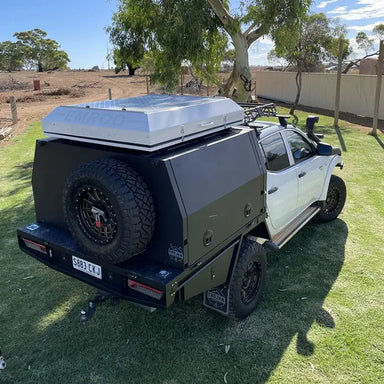 A photo of an Emroo desert king 4 person roof top tent sitting on top of a 4x4 which is on grass.