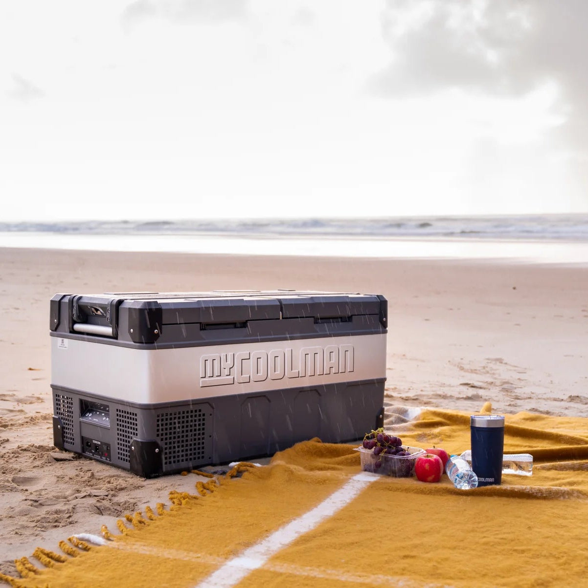A photo of a MyCOOLMAN 85L Dual Zone Portable Car and Camping Fridge on a beach