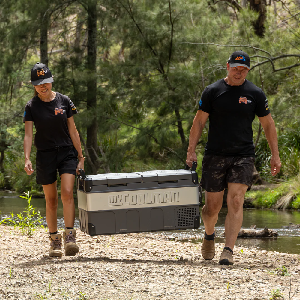 A photo of a MyCOOLMAN 85L Dual Zone Portable Car and Camping Fridge being carried by a man and a woman.