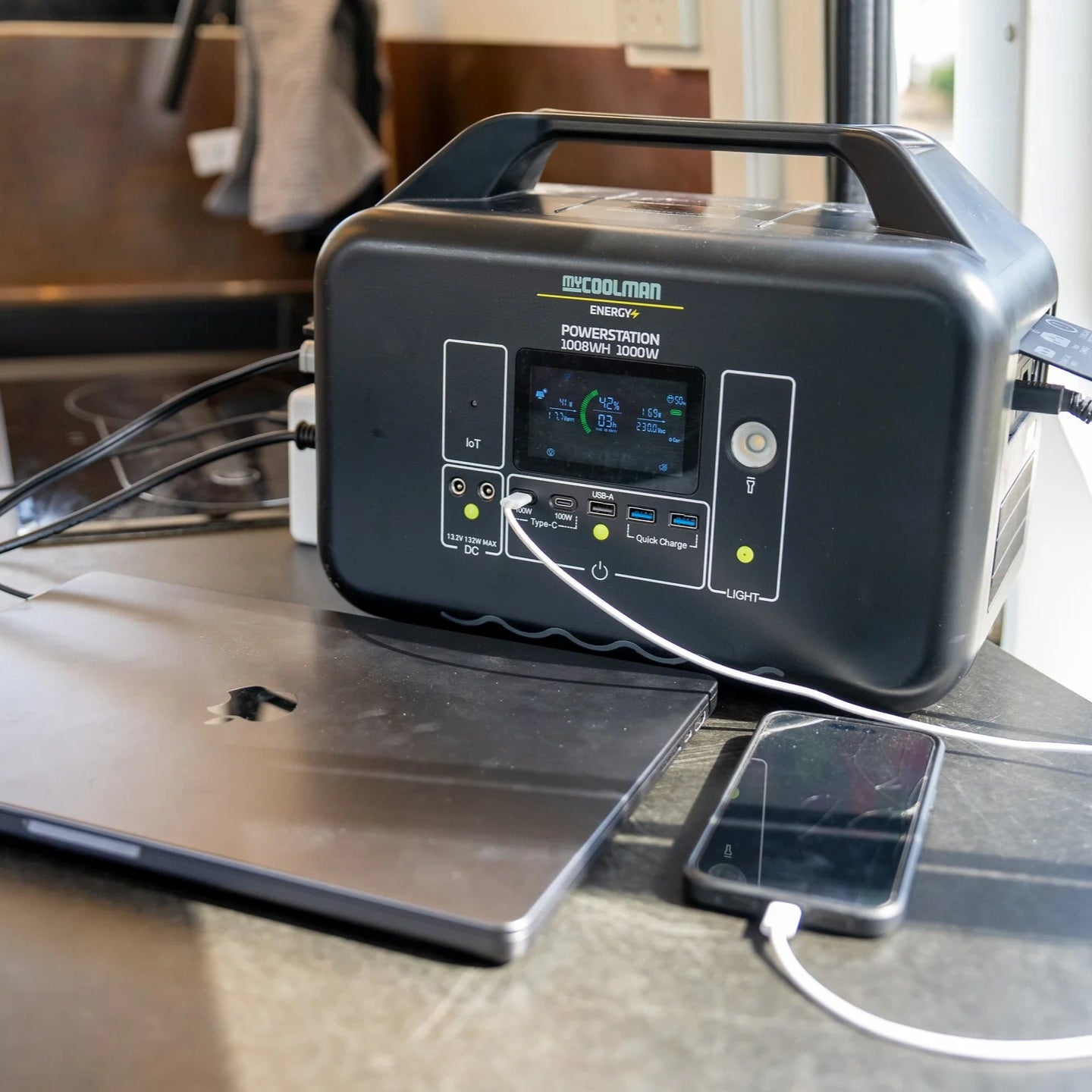 A photo of a MyCOOLMAN 1000W 78Ah Portable Power Station charging a laptop and a smart phone.