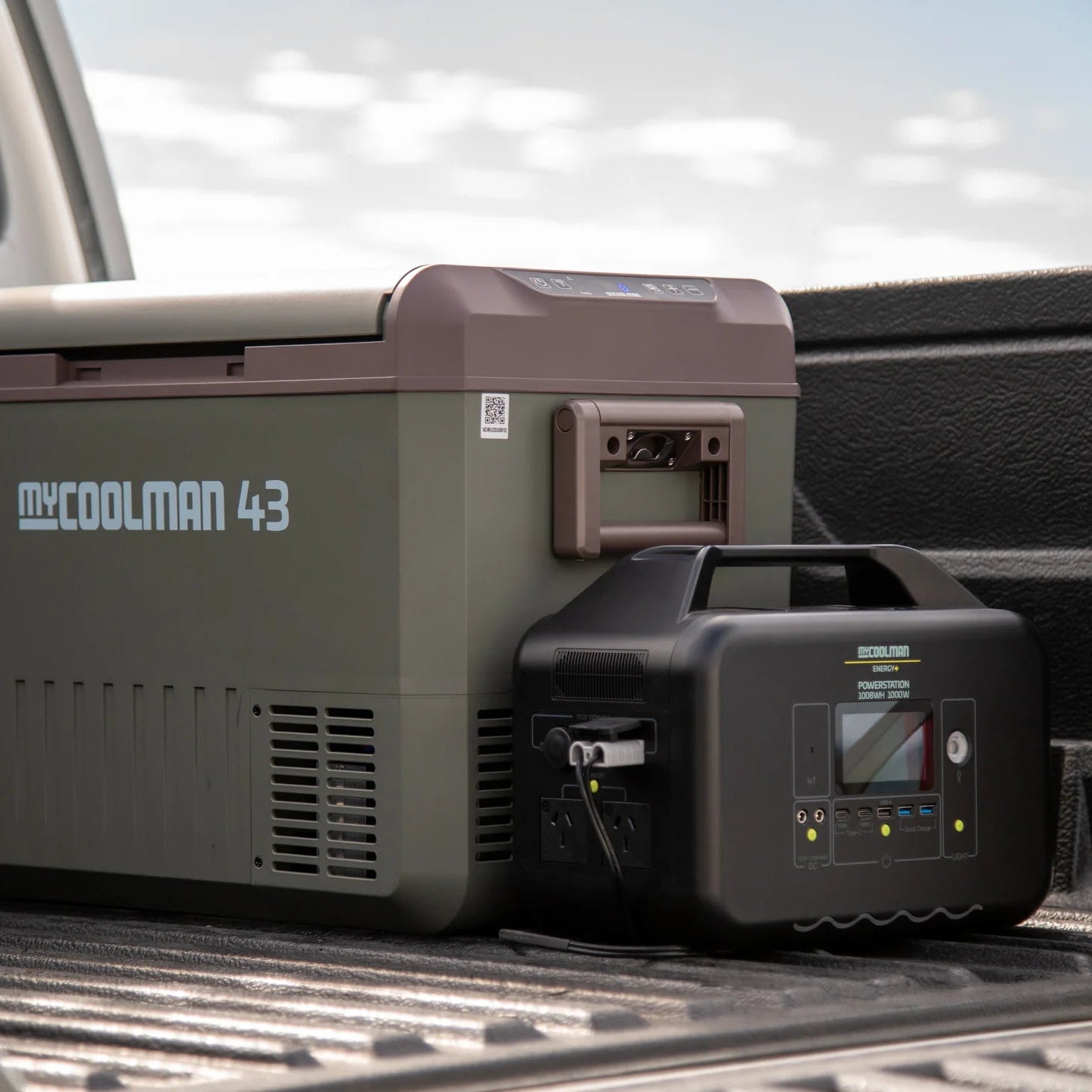A photo of a MyCOOLMAN 1000W 78Ah Portable Power Station sitting next to a mycoolman fridge in the tray of a ute.