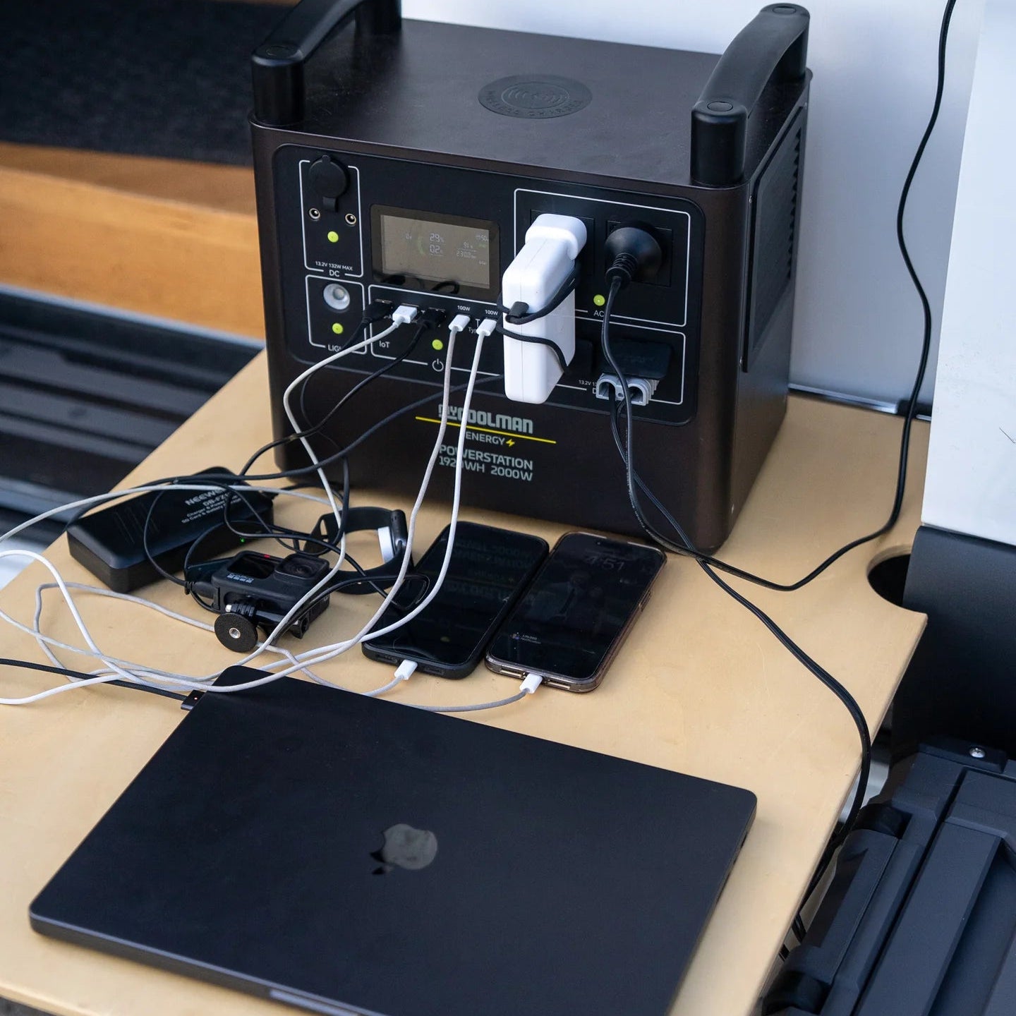 A photo of a mycoolman 2000W 150ah portable power station charging a laptop and several smart devices.