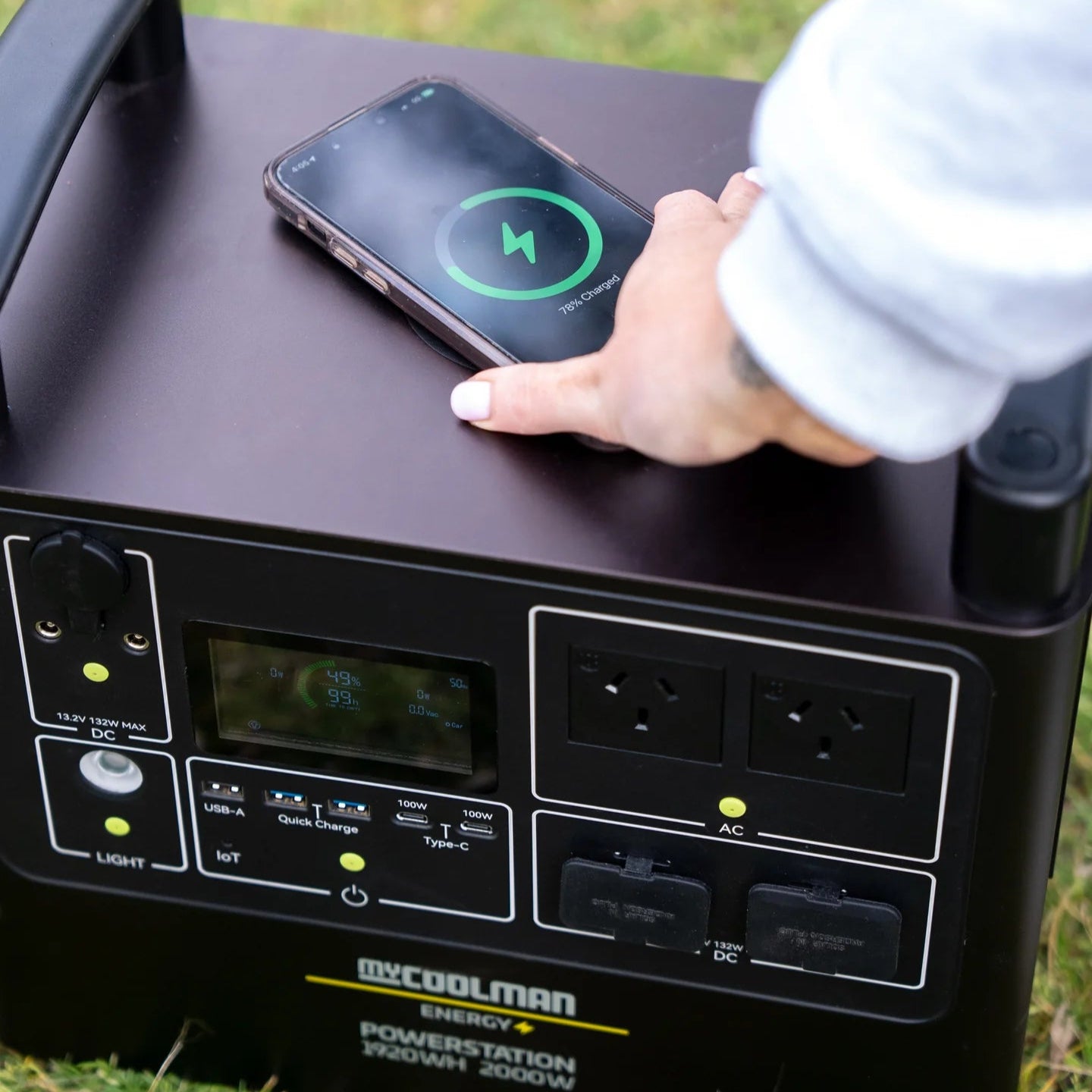 A photo of a mycoolman 2000W 150ah portable power station charging a phone via its wireless feature.