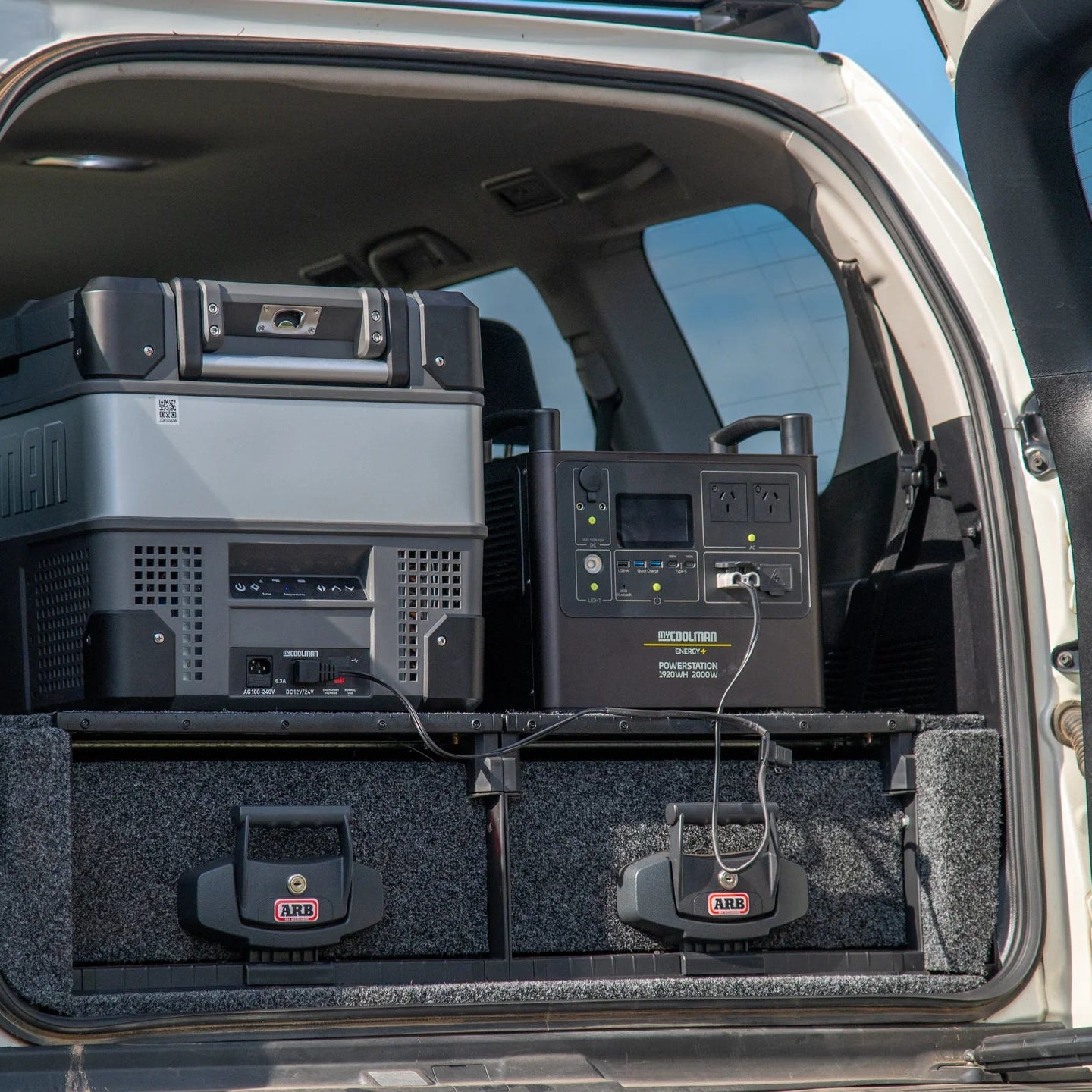 A photo of a mycoolman 2000W 150ah portable power station sitting in the back of a van next to a mycoolman fridge.