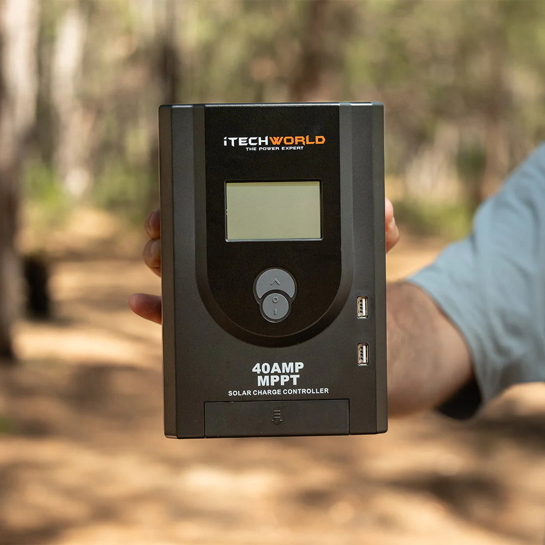 Black iTechWorld 40A MPPT solar charge controller with digital display being held by a man outdoors.