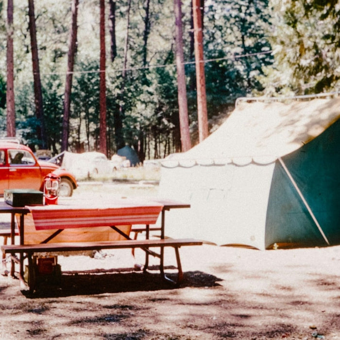 A photo of a camping site with a vintage car in the background.