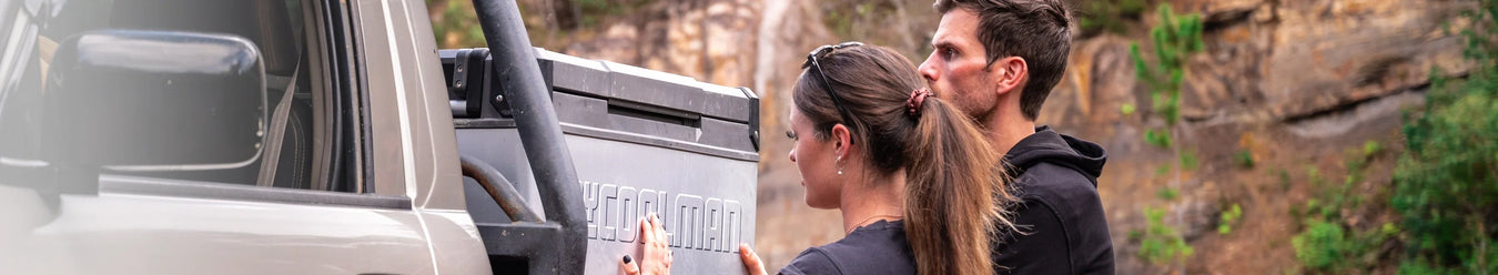 A mycoolman camping fridge next to a man and a woman.