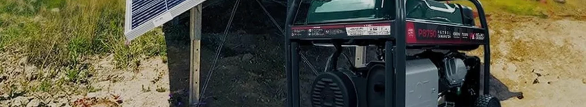 A portable petrol generator on a grassy field.