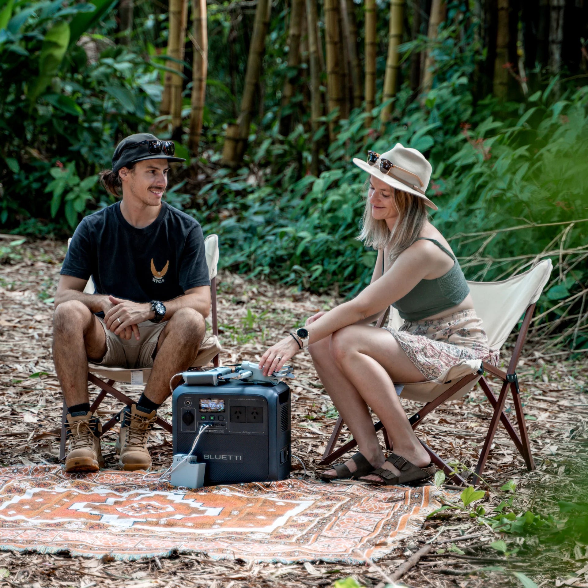 A photo of a lady and a man outside on camp chairs sitting next to a Bluetti AC180P Solar Portable Power Station