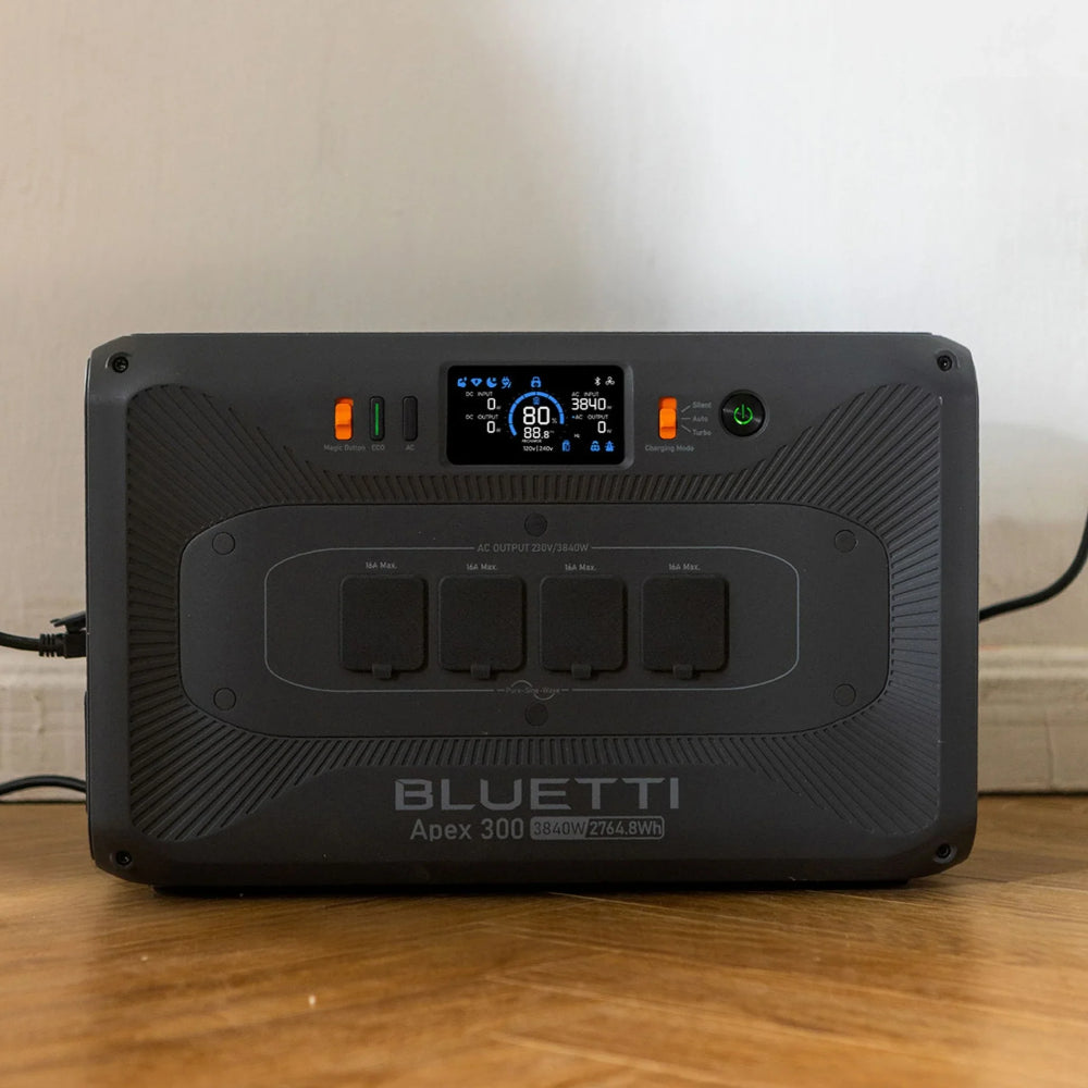 A photo of a Bluetti Apex 300 home battery backup sitting on a wooden floor with a white wall background