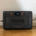 A photo of a Bluetti Apex 300 home battery backup sitting on a wooden floor with a white wall background