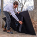 A photo of a man holding up a bluetti PV350 350W solar panel out in the bush.