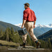 A photo of a man hiking outdoors carrying a Bluetti premium 100v2 1800w power station with one hand.