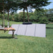 A photo of an EcoFlow 400W solar panel sitting on a bank of grass outdoors next to a table with food and appliances.