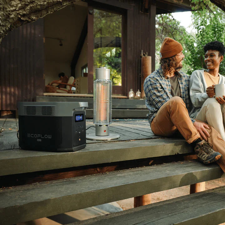 A photo of an EcoFlow Delta 2 Max Portable Power Station on a wooden deck, plugged into a light with two people sitting alongside.