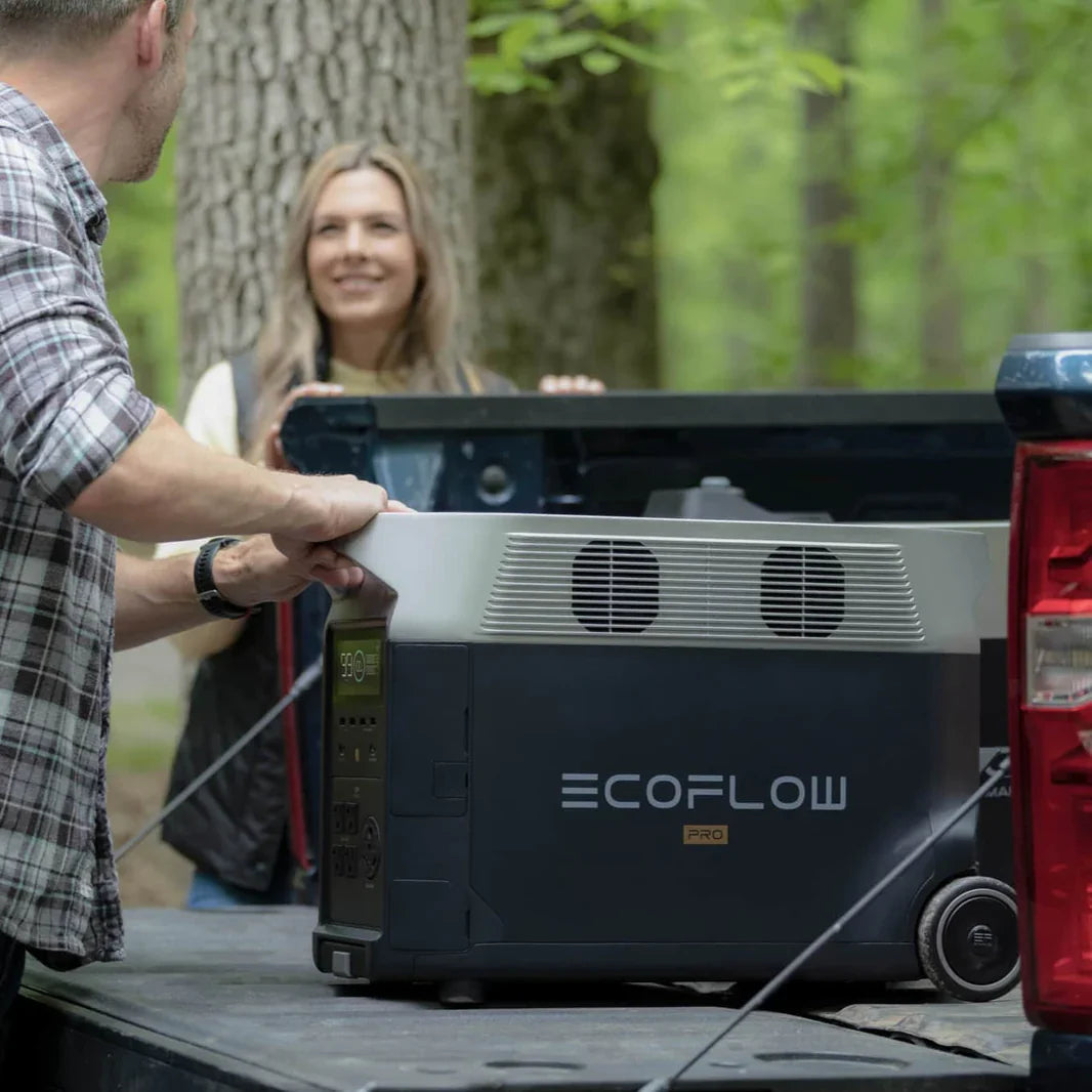 A photo of an EcoFlow Delta Pro portable power station sitting outdoors with a man holding it and a woman in the background.