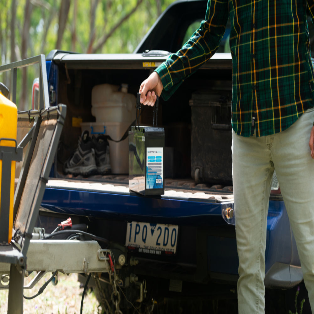 A man with an Invicta Lithium 24V Battery at the back of the car
