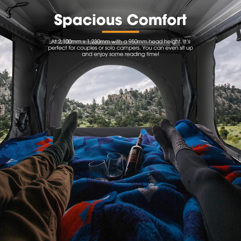 A photo of a couple sitting in their san hima jervis loft pop up hard shell roof top tent with two glasses of wine and a wine bottle.