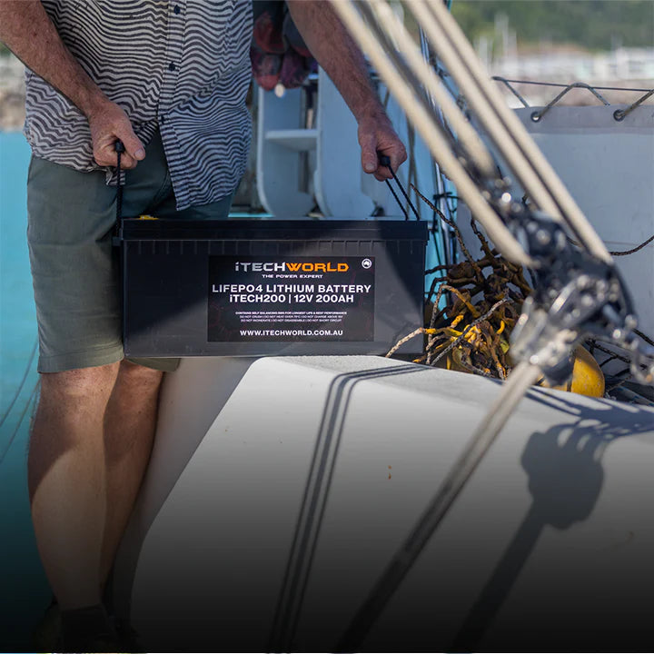 A photo of a man holding an iTechWorld 200ah deep cycle lithium battery inside of a boat.
