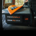 A photo of an iTechWorld 2000W pro power inverter sitting inside of a van with an orange surf board on top of it.