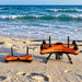 In the image an orange swellpro fd3s and its remote in the beach