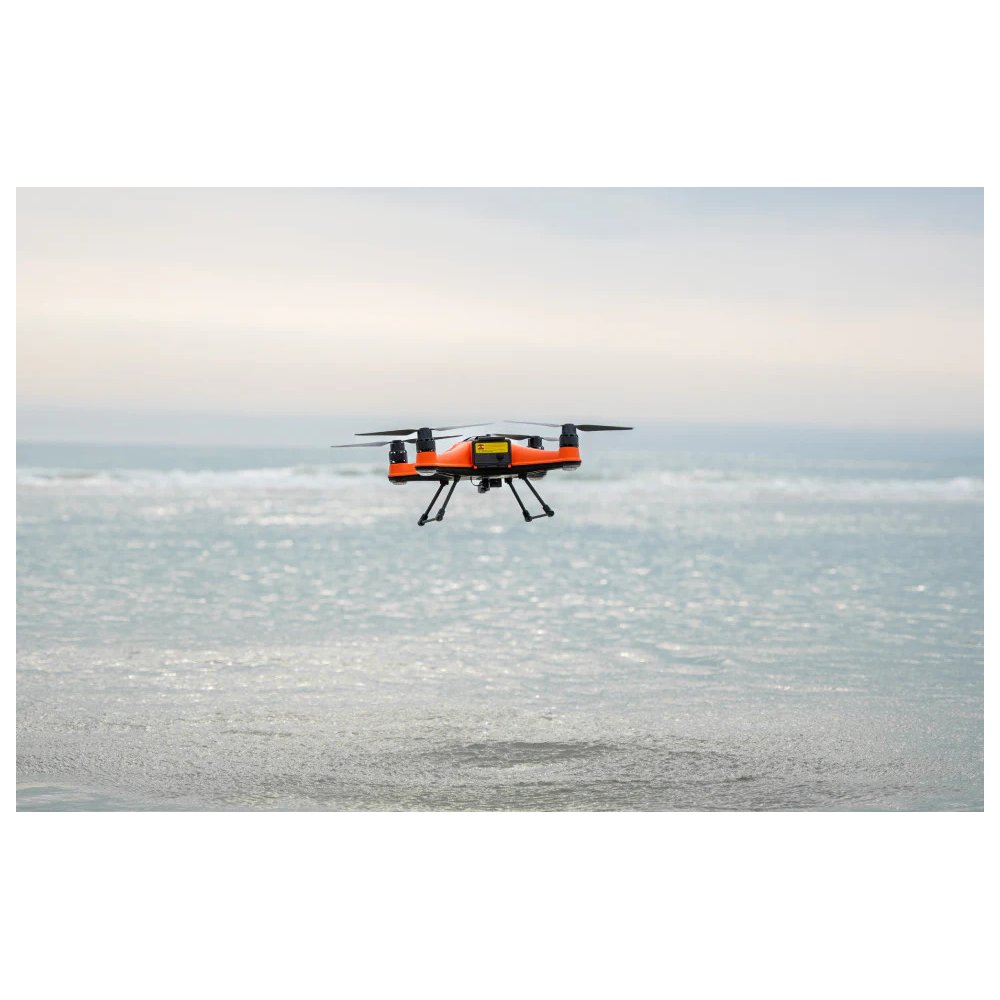 SwellPro Fisherman FD1S fishing drone hovering low over breaking surf on an overcast day.
