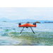 SwellPro Fisherman FD1S fishing drone lifting off the sea surface with water dripping from its landing gear and a rocky coastline behind.