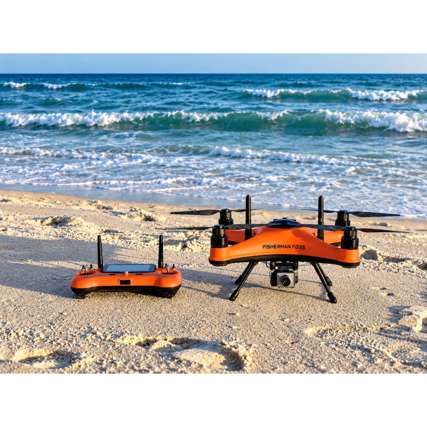 SwellPro Fisherman FD3S fishing drone standing on a sandy beach beside its orange remote controller, with breaking surf behind.