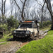A Toyota LandCruiser 79 Series dual cab driving through mud on a bush track.