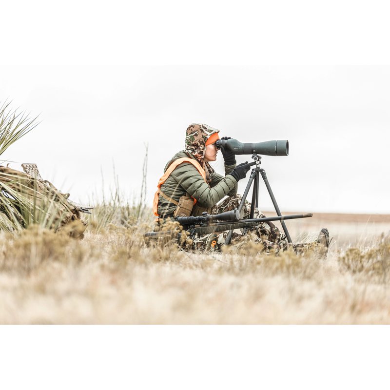 Hunter glassing open country with the Viper 20-60x85 Straight Scope on a tripod beside a rifle, tripod sold separately